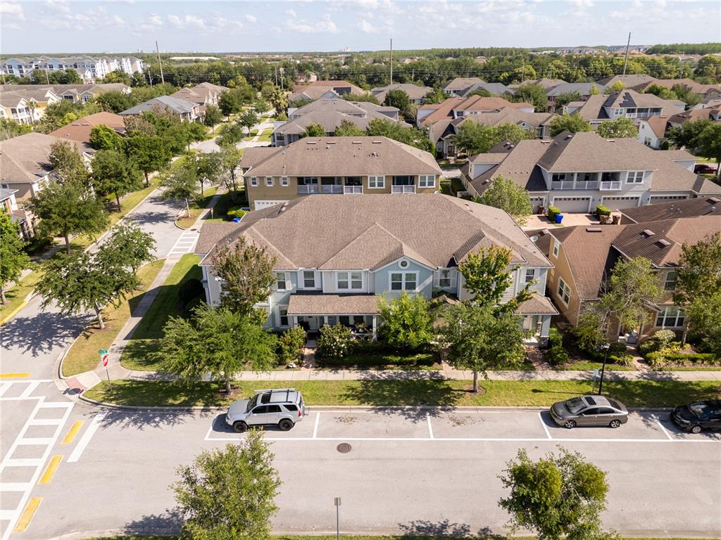 An aerial view shows a multi-unit residential building with a brown roof and street parking — 2573 FOLIO WAY, KISSIMMEE, FL