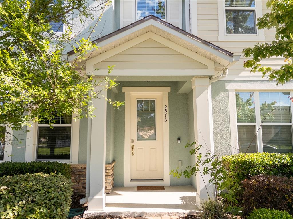 The exterior of a house features a covered entryway with a light-colored door and columns — 2573 FOLIO WAY, KISSIMMEE, FL