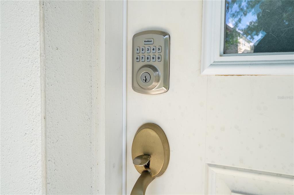 A close-up view of a white door featuring a Kwikset electronic keypad deadbolt and handle — 2573 FOLIO WAY, KISSIMMEE, FL