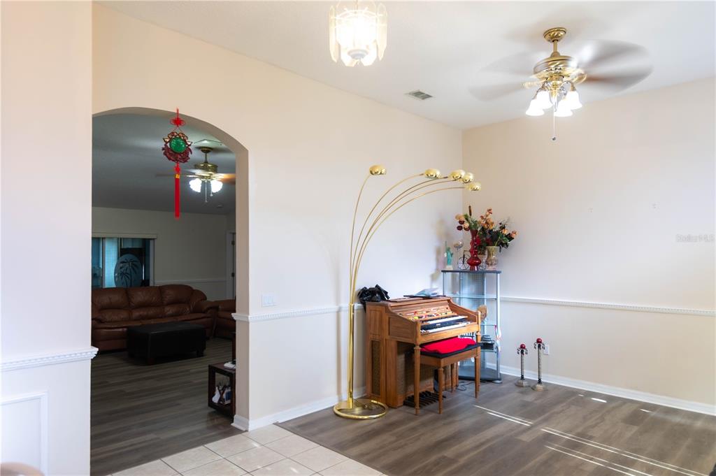 A room with a wooden organ, a tall floor lamp, and an arched entryway to another room — 1306 ISLAND COVE DRIVE, DELAND, FL