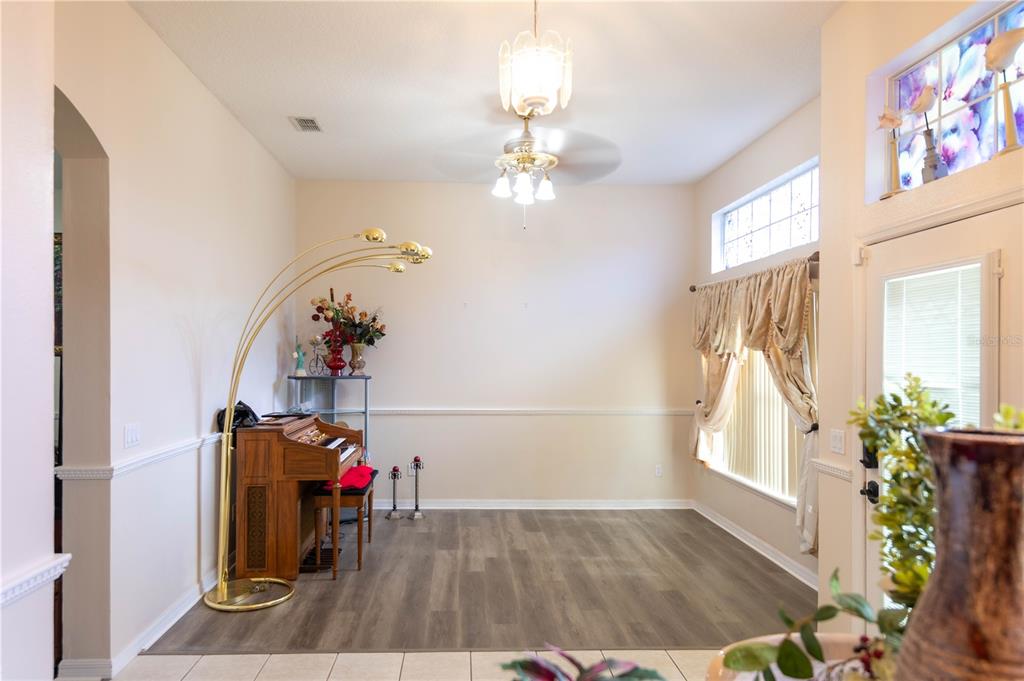 A dining room with wood-look flooring, a piano, a floor lamp, and a chandelier — 1306 ISLAND COVE DRIVE, DELAND, FL