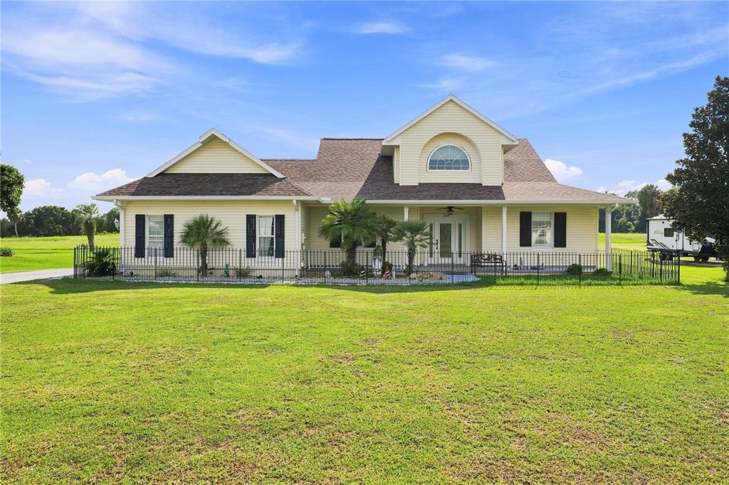 A light yellow, single-story suburban house with a fenced front yard and a large lawn — 1375 TIMUCUAN, INVERNESS, FL