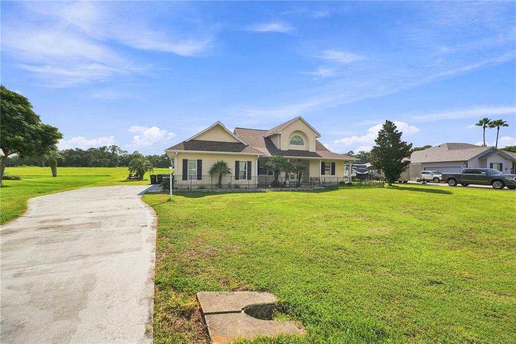 A yellow single-story house with a concrete driveway and a large front lawn — 1375 TIMUCUAN, INVERNESS, FL