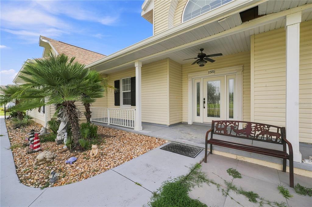 A yellow-sided house features a covered front porch with a bench and a palm tree — 1375 TIMUCUAN, INVERNESS, FL