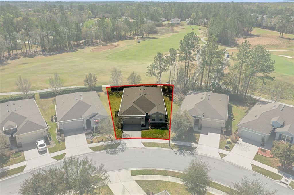 An aerial view shows a single-family home outlined in red, situated on a golf course — 17807 GARSALASO CIRCLE, BROOKSVILLE, FL