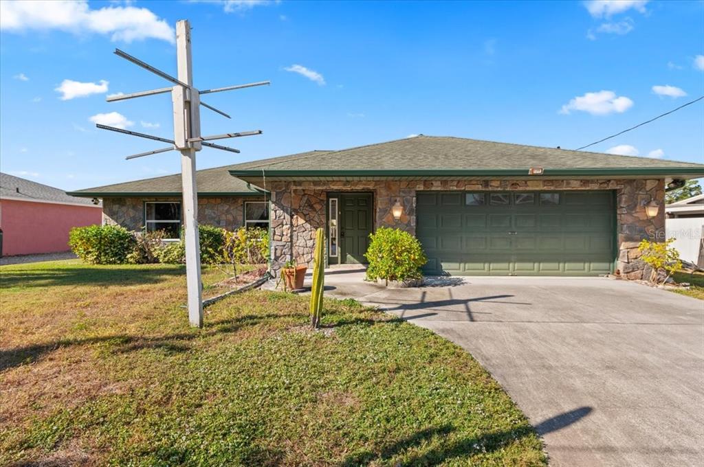 A single-story house with a stone facade, green roof, and an attached two-car garage — 1560 INGRAM AVENUE, SARASOTA, FL