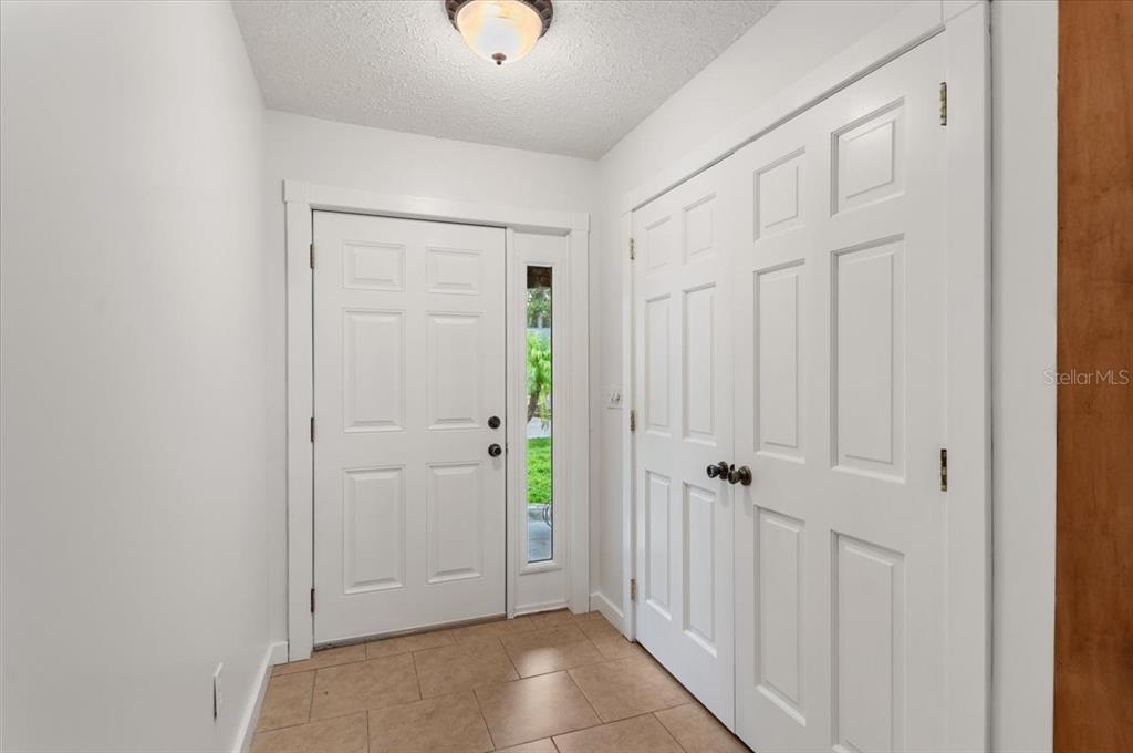 An entryway features a wooden front door, a matching double-door closet, and light-colored tile flooring — 1560 INGRAM AVENUE, SARASOTA, FL