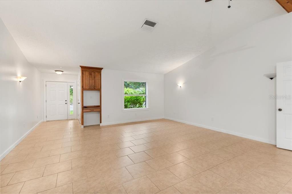 A living room features light green walls, tan tile flooring, and a built-in wooden desk — 1560 INGRAM AVENUE, SARASOTA, FL