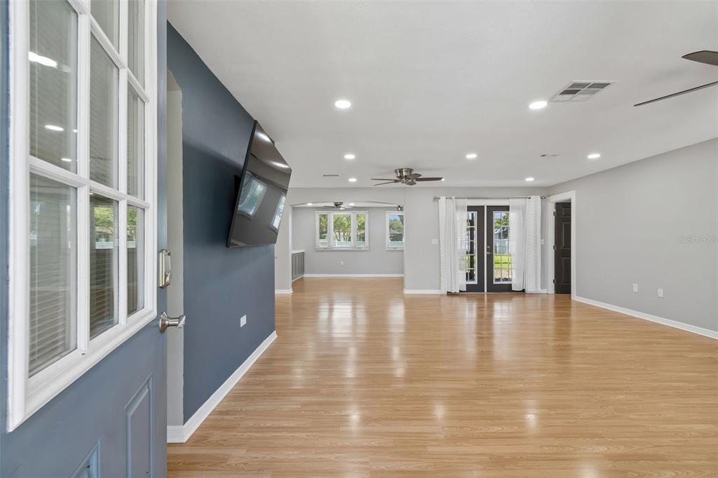 An open-concept living area features light wood flooring, a dark blue accent wall, and recessed lighting — 9329 AMAZON DRIVE, NEW PORT RICHEY, FL