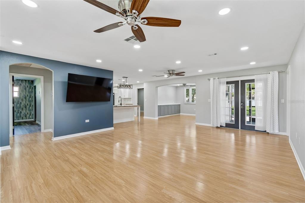 A spacious living room with light wood floors, a blue accent wall, and French doors — 9329 AMAZON DRIVE, NEW PORT RICHEY, FL