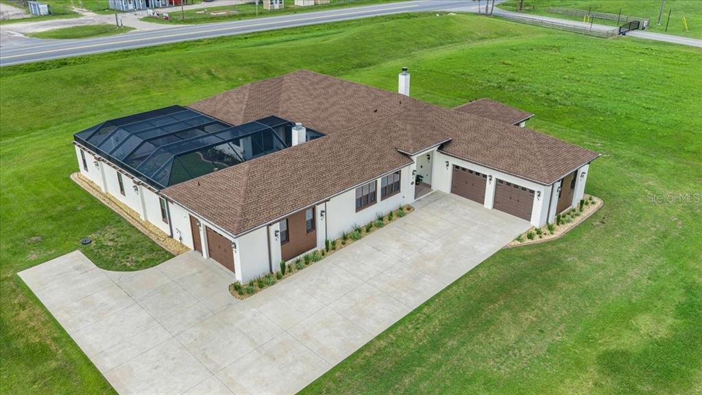 An aerial view shows a single-story house with a screened-in pool and a three-car garage — 1866 NW 79TH LOOP, OCALA, FL