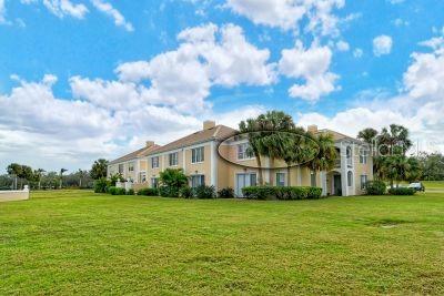 A multi-story apartment building with beige siding sits on a large, grassy lawn — 51 MACEWEN DRIVE UNIT 12, OSPREY, FL