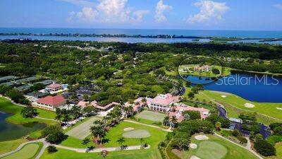 An aerial view shows a large estate with a golf course, lake, and distant ocean — 51 MACEWEN DRIVE UNIT 12, OSPREY, FL