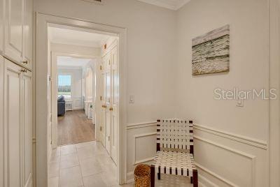 A hallway with white wainscoting, a woven chair, and a doorway leading to another room — 51 MACEWEN DRIVE UNIT 12, OSPREY, FL