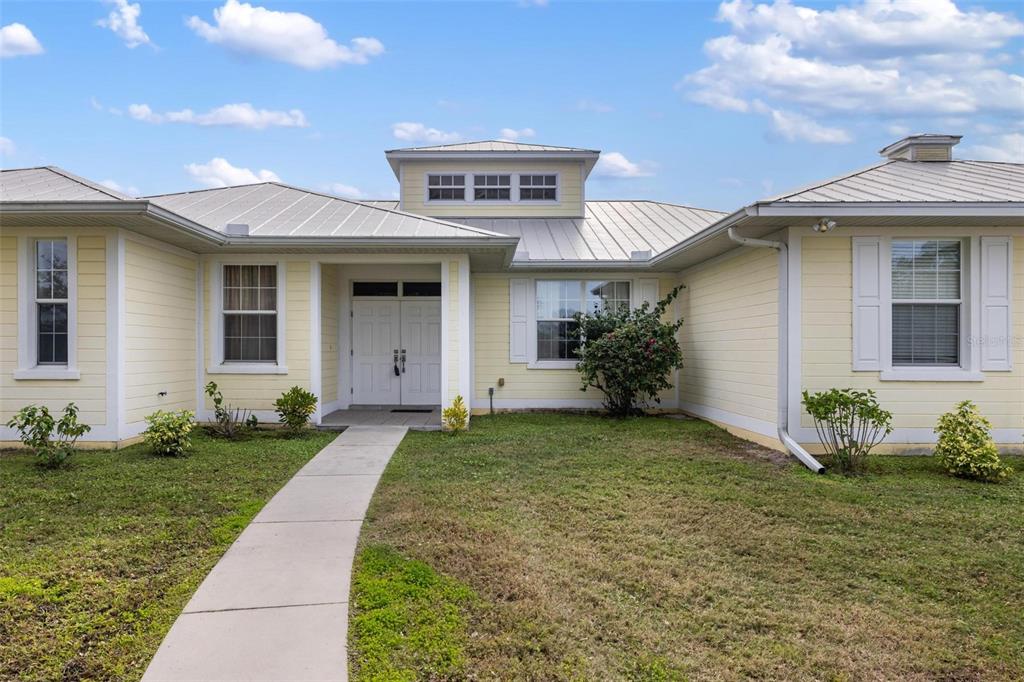 A single-story house with yellow siding, a metal roof, and a central entryway — 8069 SW AVIARY ROAD, ARCADIA, FL
