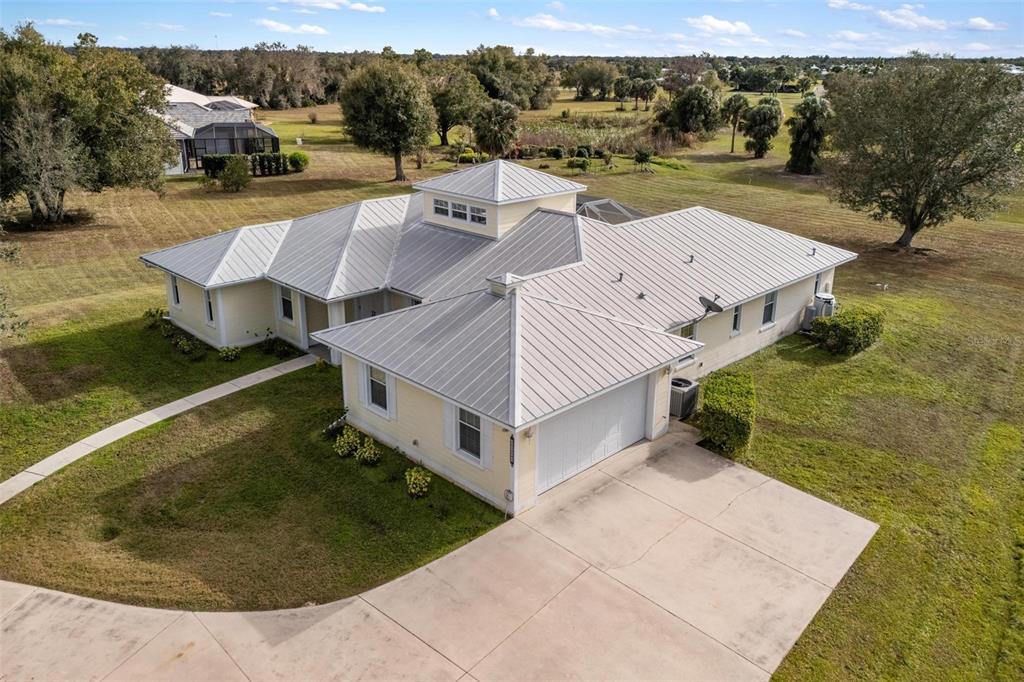 An aerial view of a light yellow house with a metal roof and concrete driveway — 8069 SW AVIARY ROAD, ARCADIA, FL
