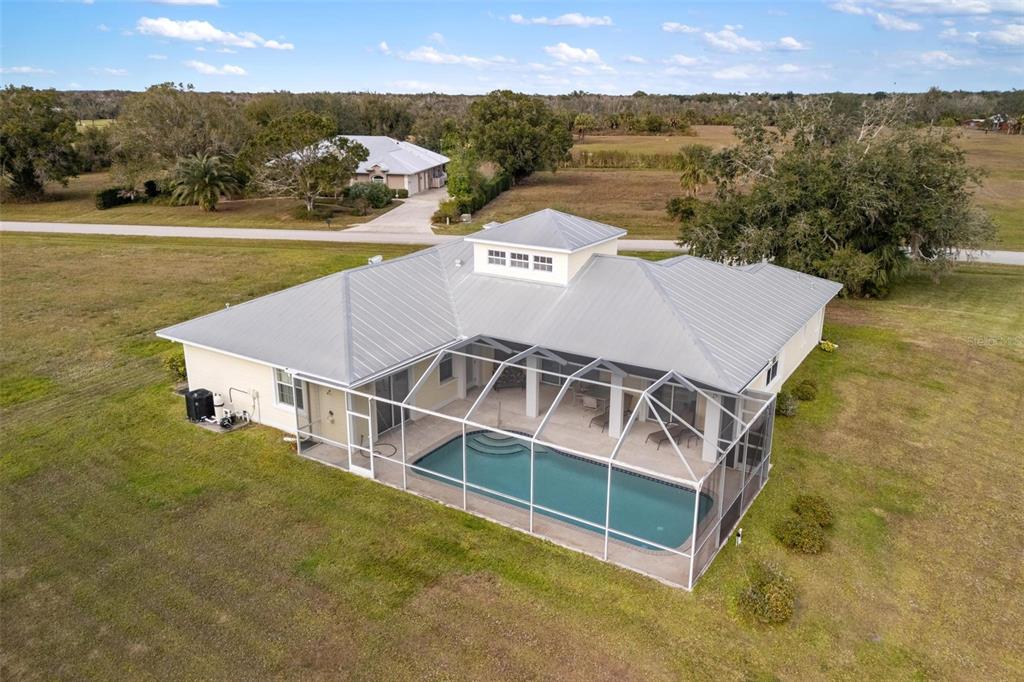 An aerial view of a single-story house with a metal roof and a screened pool — 8069 SW AVIARY ROAD, ARCADIA, FL