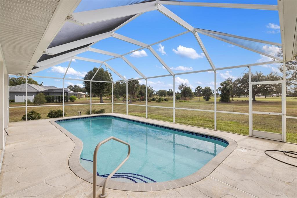 A screened-in pool enclosure with a concrete patio overlooking a grassy backyard — 8069 SW AVIARY ROAD, ARCADIA, FL