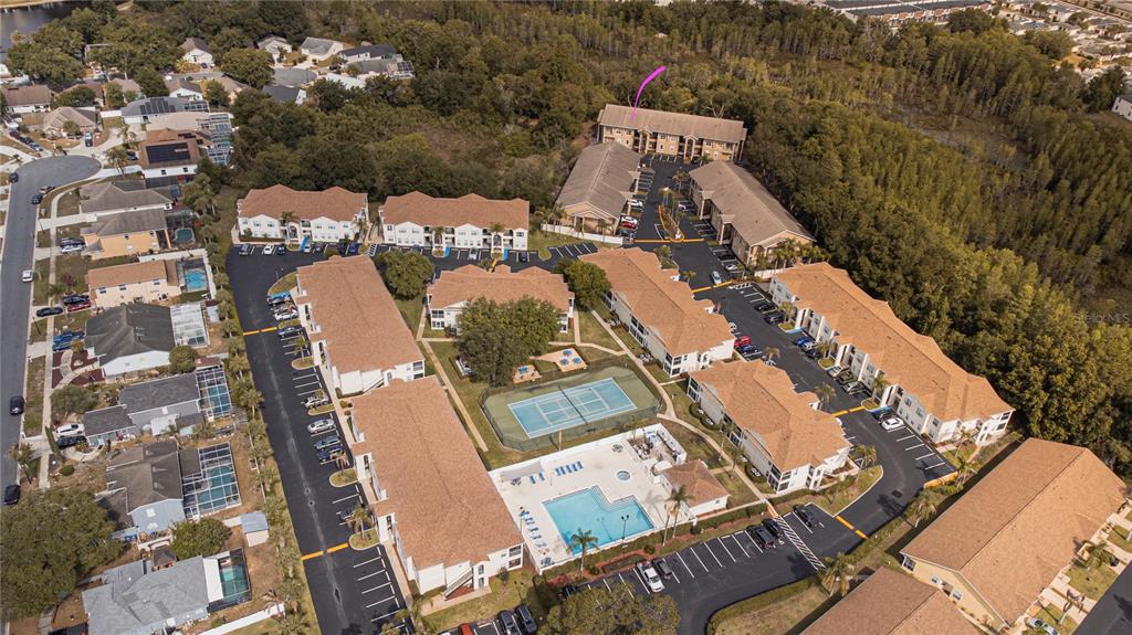 An aerial view shows a multi-building apartment complex with a central pool and tennis court — 8838 CORAL PALMS COURT UNIT B, KISSIMMEE, FL