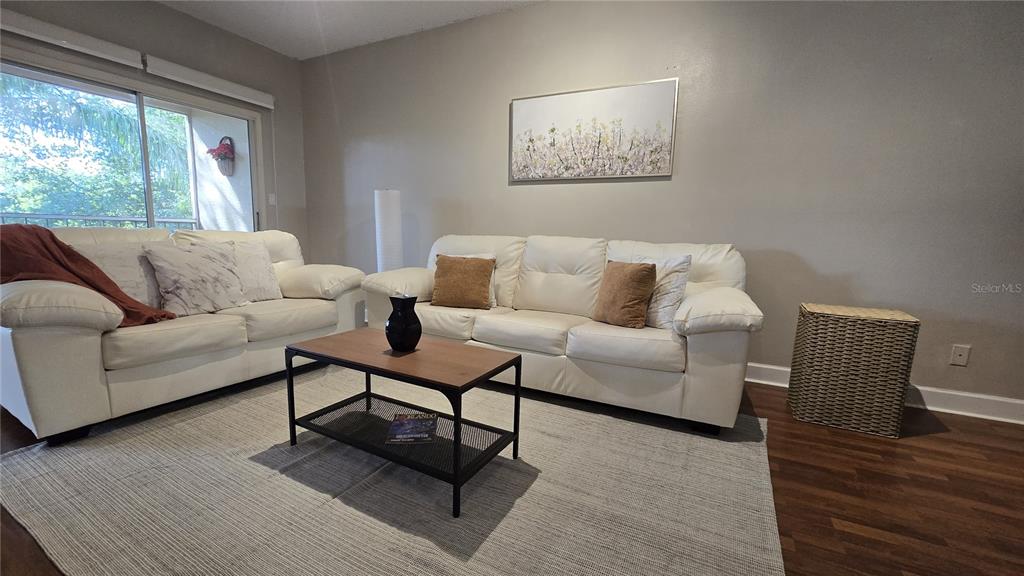 A living room features two white leather sofas, a coffee table, and a large area rug — 8838 CORAL PALMS COURT UNIT B, KISSIMMEE, FL