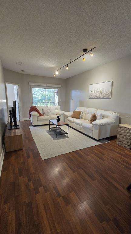 A living room features white sofas, a coffee table, wood-look flooring, and track lighting — 8838 CORAL PALMS COURT UNIT B, KISSIMMEE, FL