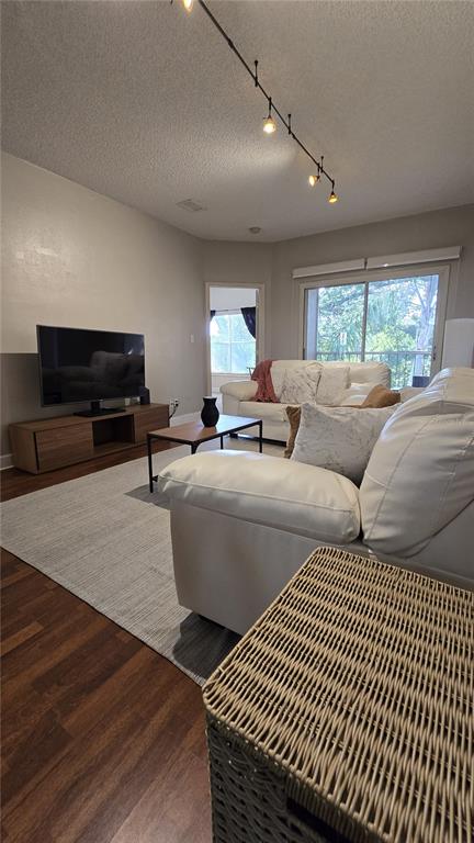 A living room features white leather sofas, a television on a wooden console, and track lighting — 8838 CORAL PALMS COURT UNIT B, KISSIMMEE, FL