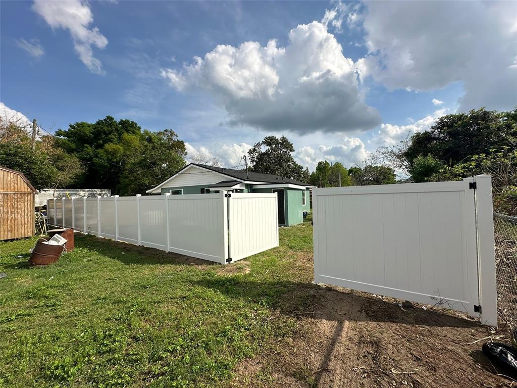 A white vinyl privacy fence encloses a backyard with a house in the background — 2015 1/2 LAUREL STREET, BARTOW, FL