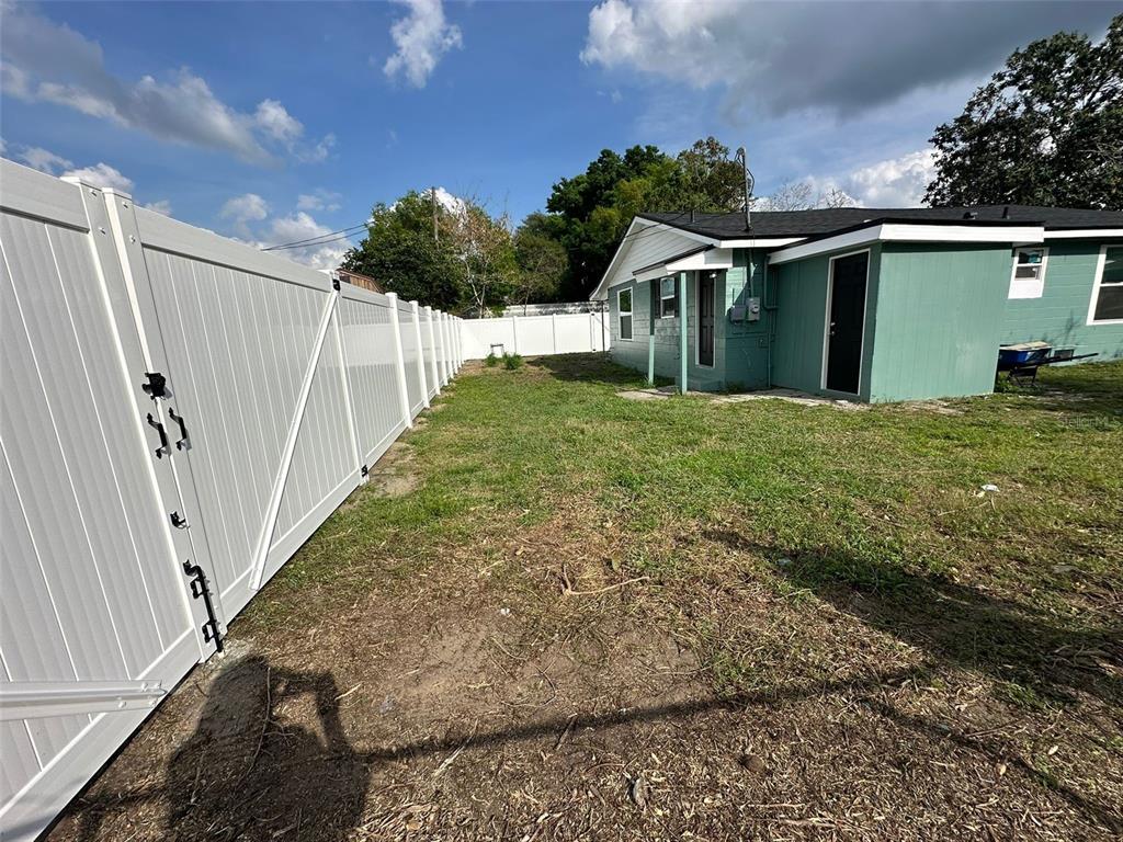 A backyard with a green house, a white vinyl fence, and patchy grass — 2015 1/2 LAUREL STREET, BARTOW, FL