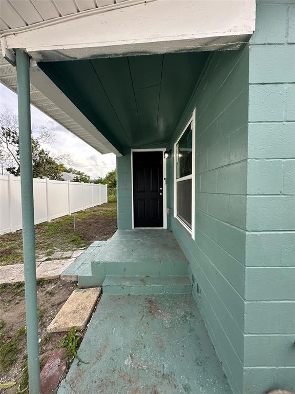 A covered concrete porch leads to a black front door on a green block house — 2015 1/2 LAUREL STREET, BARTOW, FL