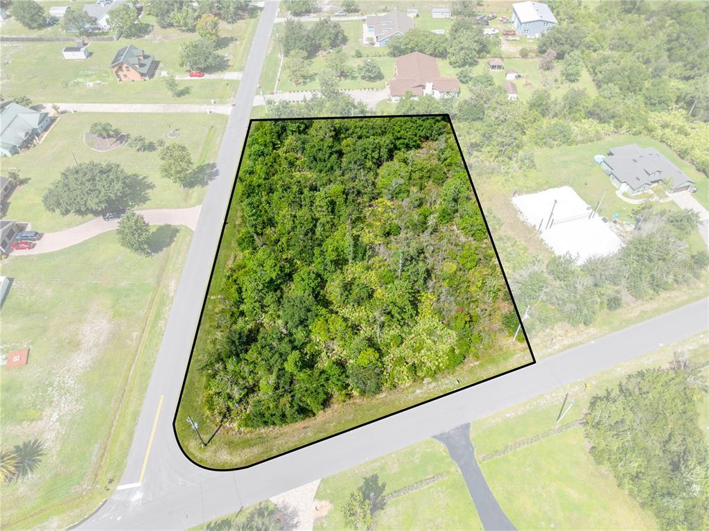 An aerial view shows a wooded, trapezoidal vacant lot bordered by two paved roads — 2240 BRONCO DR, ST CLOUD, FL