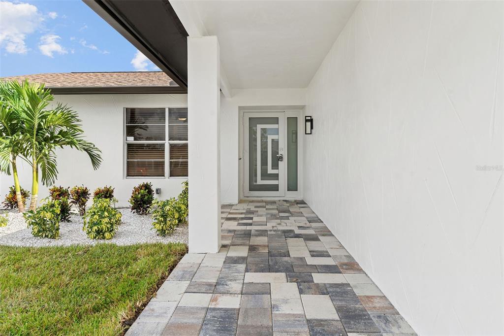 A paved walkway leads to a modern front door under a covered entryway — 5811 IMPERIAL KEY, TAMPA, FL