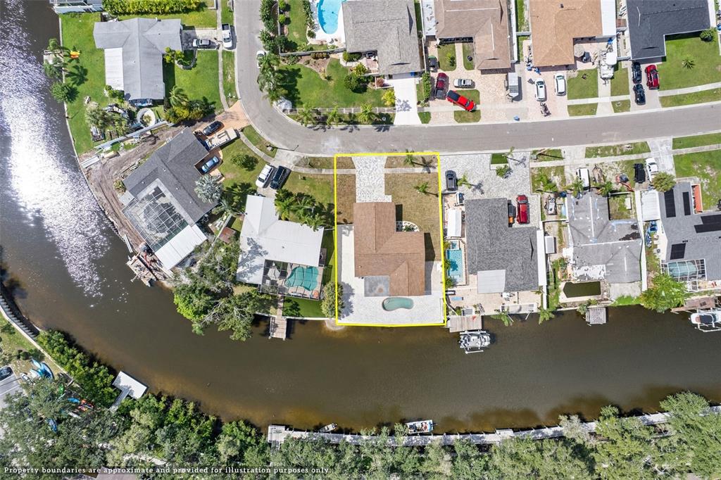 An aerial view shows a single-family home with a pool on a canal-front lot — 5811 IMPERIAL KEY, TAMPA, FL