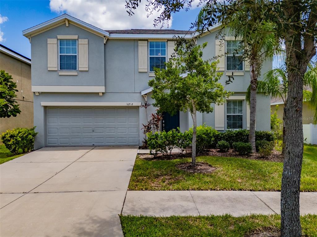 A two-story house with a gray stucco exterior, a two-car garage, and a front lawn — 16712 MYRTLE SAND DRIVE, WIMAUMA, FL
