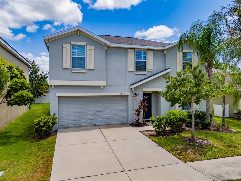 A two-story suburban house with a gray stucco exterior, a two-car garage, and a driveway — 16712 MYRTLE SAND DRIVE, WIMAUMA, FL