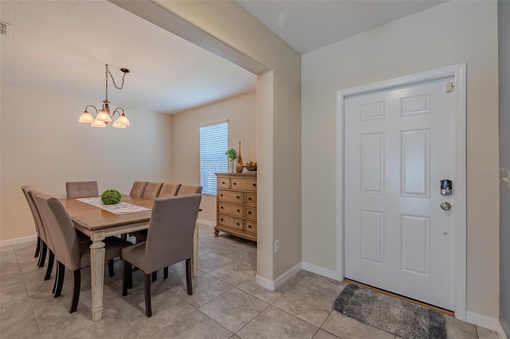 A dining room with a wooden table and chairs sits adjacent to a white front door — 16712 MYRTLE SAND DRIVE, WIMAUMA, FL