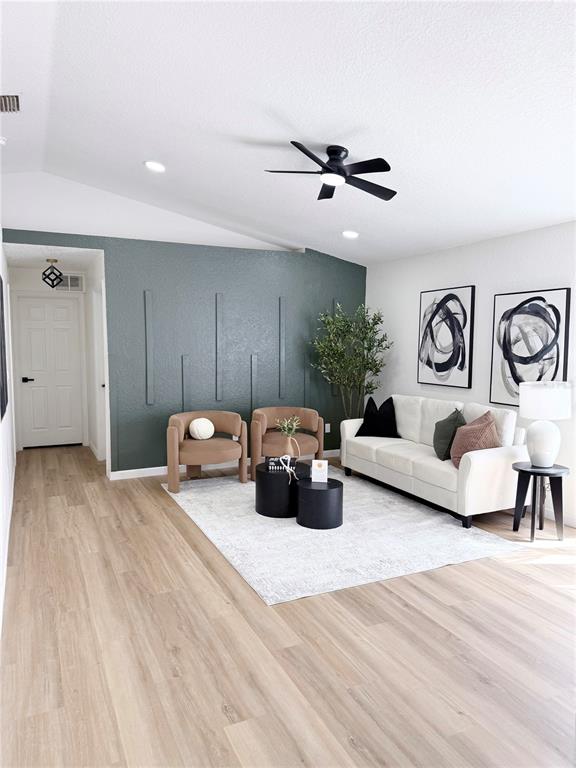A living room features a dark green accent wall with molding, a sofa, and chairs — 1112 W 7TH STREET, SANFORD, FL