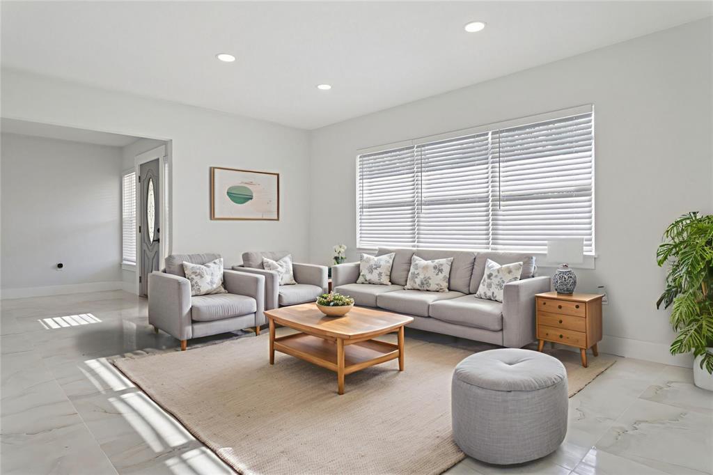 A living room features light gray furniture, a wooden coffee table, and large window blinds — 540 MILWAUKEE AVENUE, DUNEDIN, FL