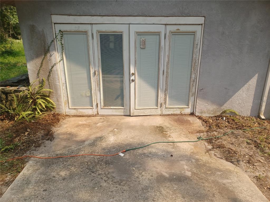A set of white French doors with integrated blinds is set into a stucco exterior wall — 155 PARSONS ROAD, LONGWOOD, FL