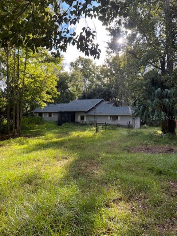 A single-story house with a gray roof sits in a grassy, tree-filled yard — 155 PARSONS ROAD, LONGWOOD, FL