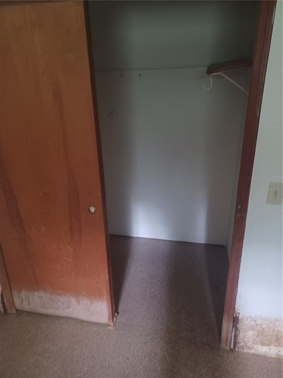 An open wooden closet door reveals a small interior space with a single hanging rod — 155 PARSONS ROAD, LONGWOOD, FL