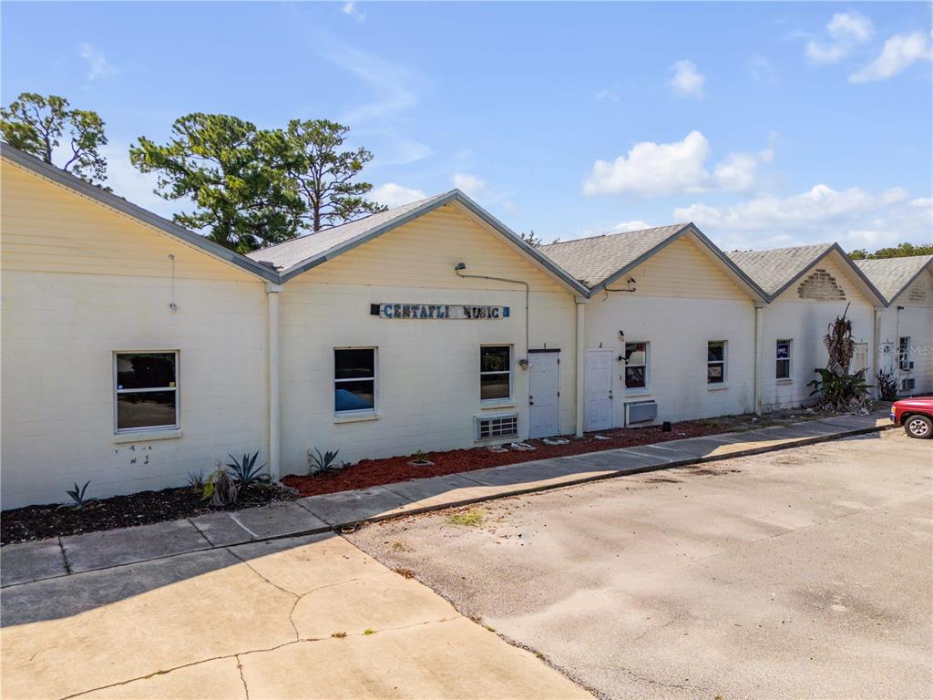 A low-rise commercial building with a light-colored facade and multiple gabled roof sections — 555 8TH STREET UNIT I, HOLLY HILL, FL