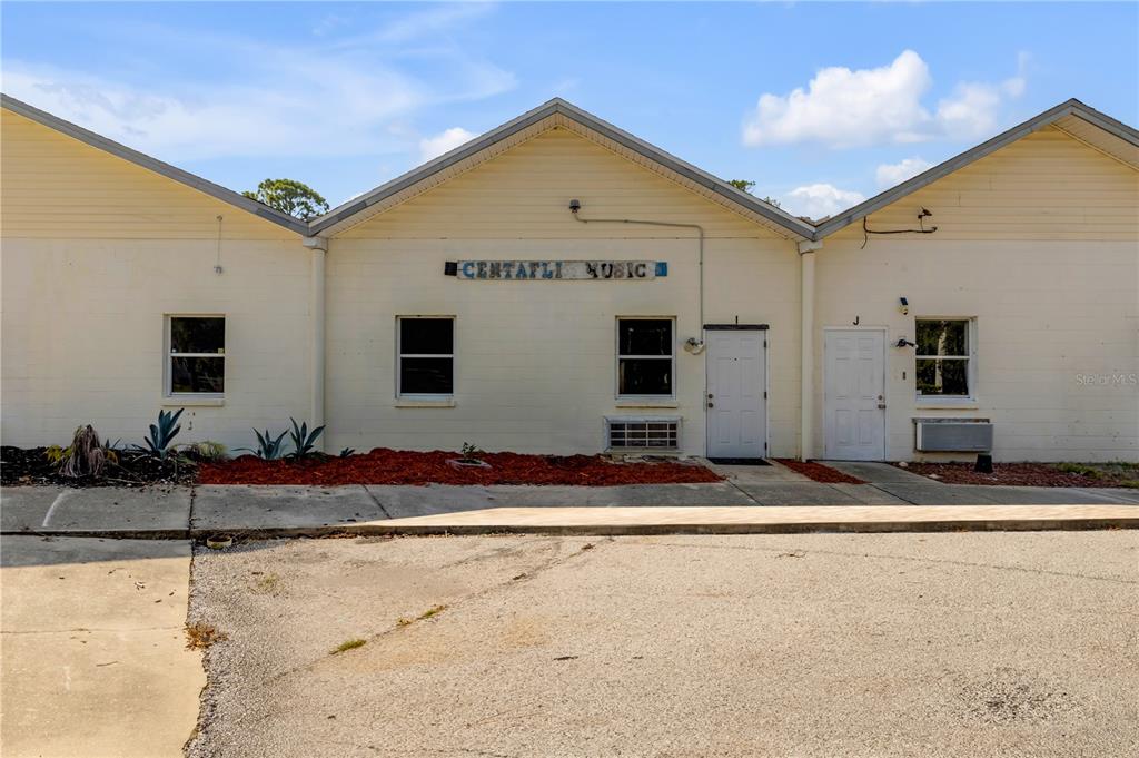 The exterior of a single-story commercial building features light-colored siding and two white entry doors — 555 8TH STREET UNIT I, HOLLY HILL, FL