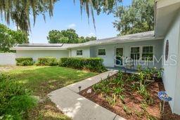 A single-story house with a light blue exterior, a concrete walkway, and a landscaped front yard — 1901 N LAKE ELOISE DRIVE, WINTER HAVEN, FL