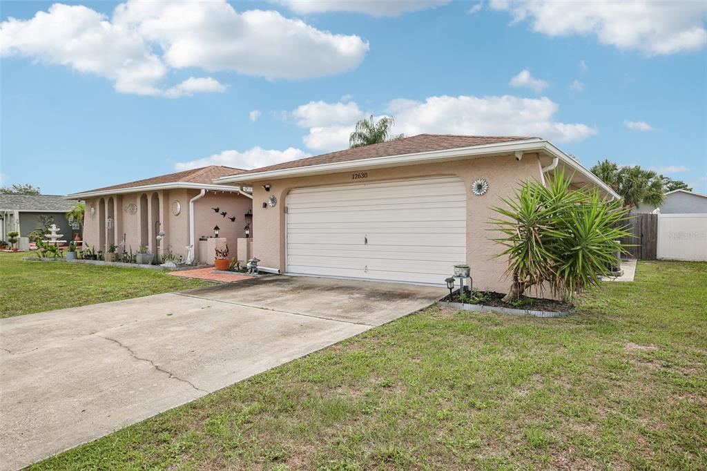 A single-story house with a beige stucco exterior, a two-car garage, and a concrete driveway — 12630 CEDAR RIDGE DRIVE, HUDSON, FL