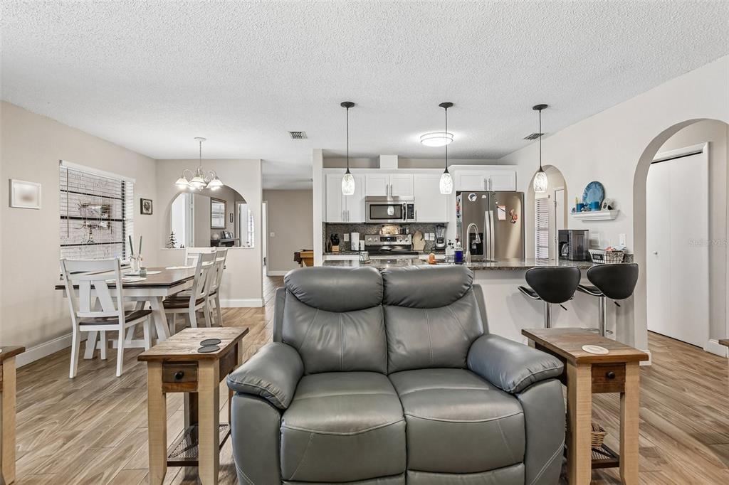 A gray leather loveseat sits in front of an open-concept kitchen and dining area — 12630 CEDAR RIDGE DRIVE, HUDSON, FL