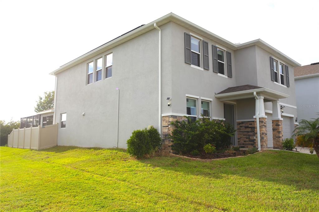 A two-story house with a stucco exterior, stone accents, and a small front porch — 2471 WARREN ACRES BOULEVARD, WESLEY CHAPEL, FL
