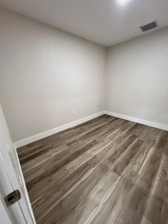 An empty room with light gray walls, white baseboards, and wood-look plank flooring — 475 UMATILLA BOULEVARD, UMATILLA, FL