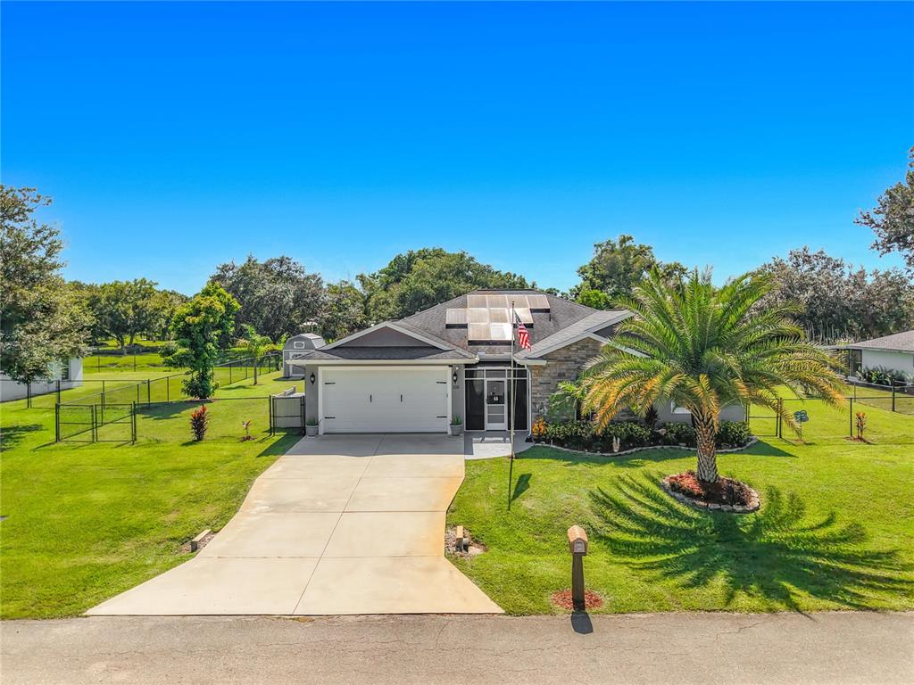 A single-story house with a two-car garage, solar panels, and a palm tree in front — 108 OAK KNOLLS CIRCLE, SEBRING, FL