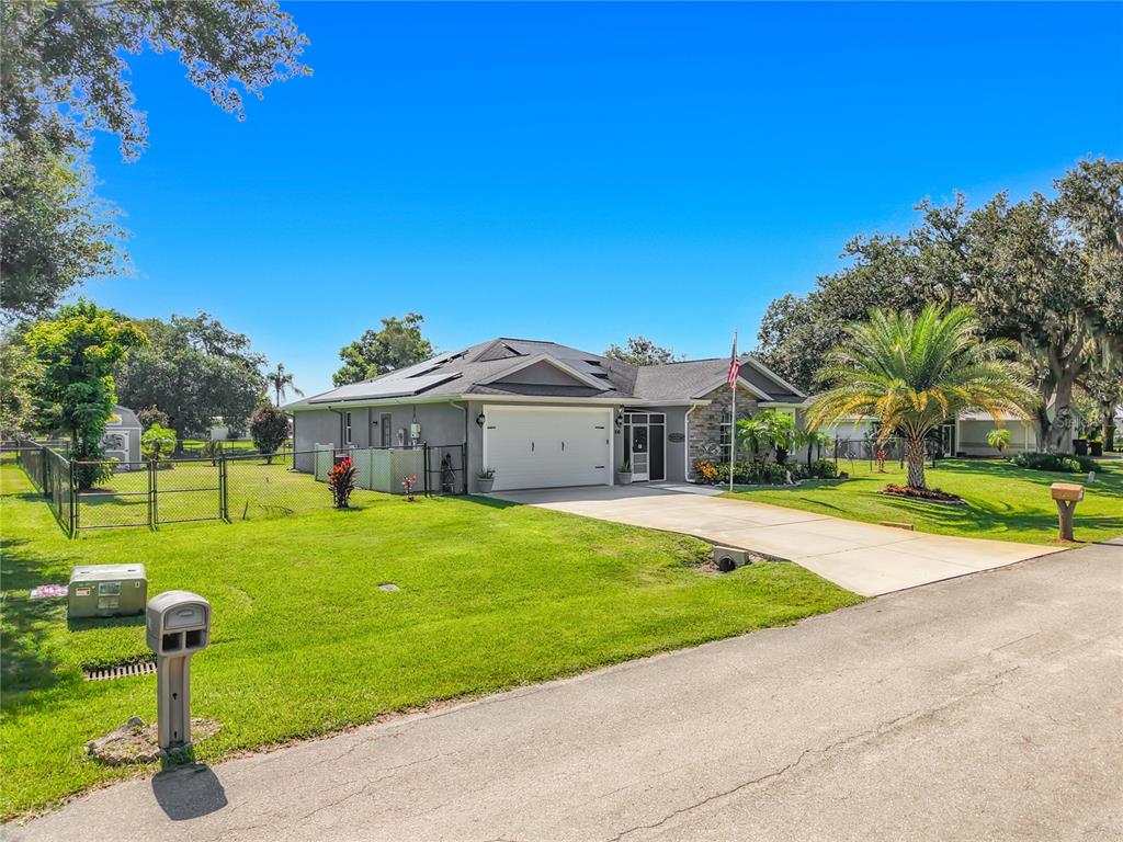 A single-story house with a two-car garage, solar panels, and a fenced yard — 108 OAK KNOLLS CIRCLE, SEBRING, FL
