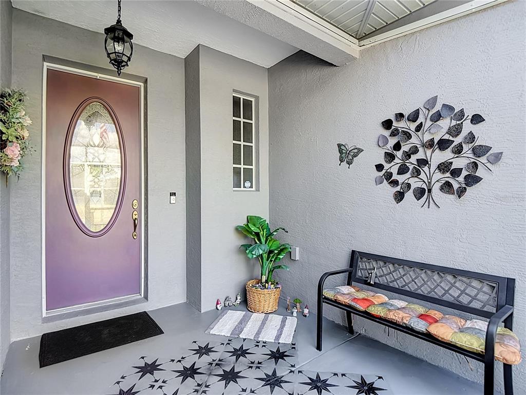 A covered entryway features a purple door, a metal bench, and wall-mounted metal art — 108 OAK KNOLLS CIRCLE, SEBRING, FL